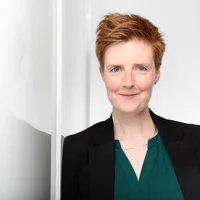 Das Foto zeigt Heike Ortlieb an einer durchsichtigen Glaswand lehnend