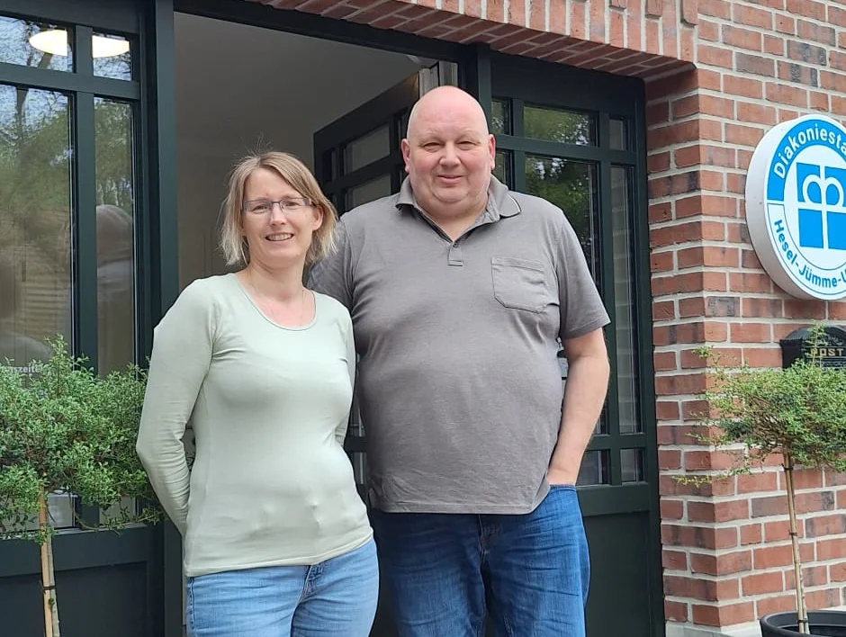 Marcus Schumacher und Eva Schulte stehen vor dem Eingang des Gebäudes der Diakoniestation Hesel-Jümme-Uplengen gGmbH in Niedersachsen