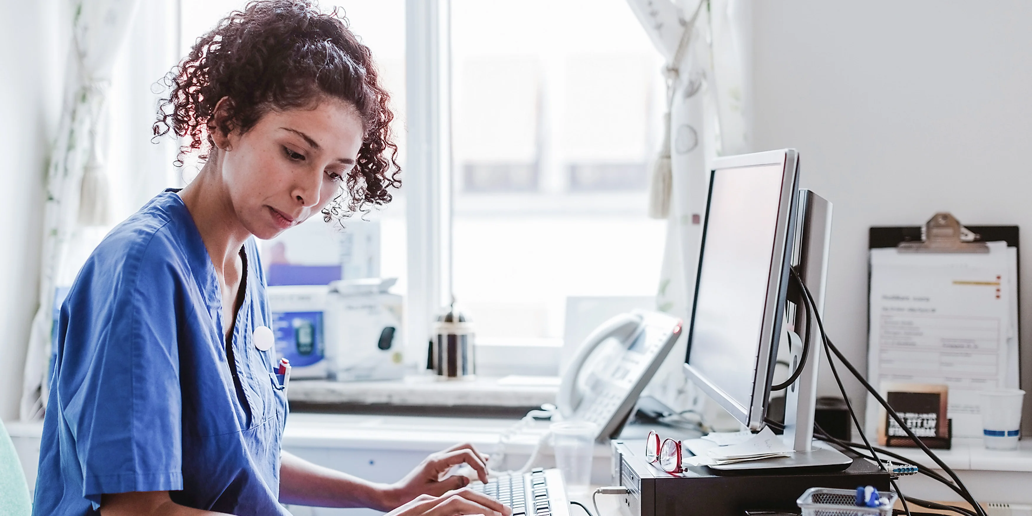 Seitenansicht einer Krankenschwester, die einen medizinischen Bericht am Computer in einer Klinik erstellt