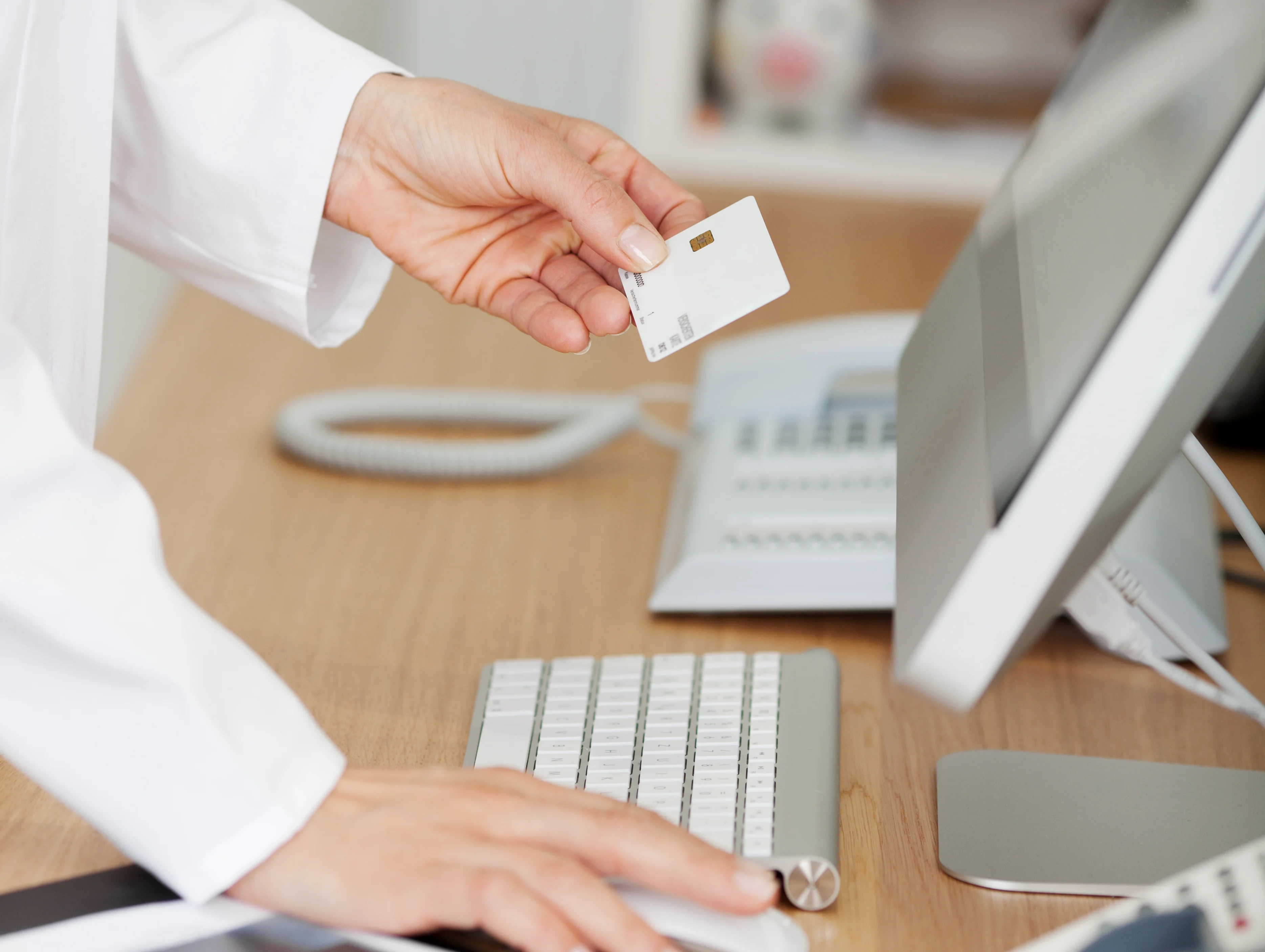 Arzthelferin mit Gesundheitskarte am Computer