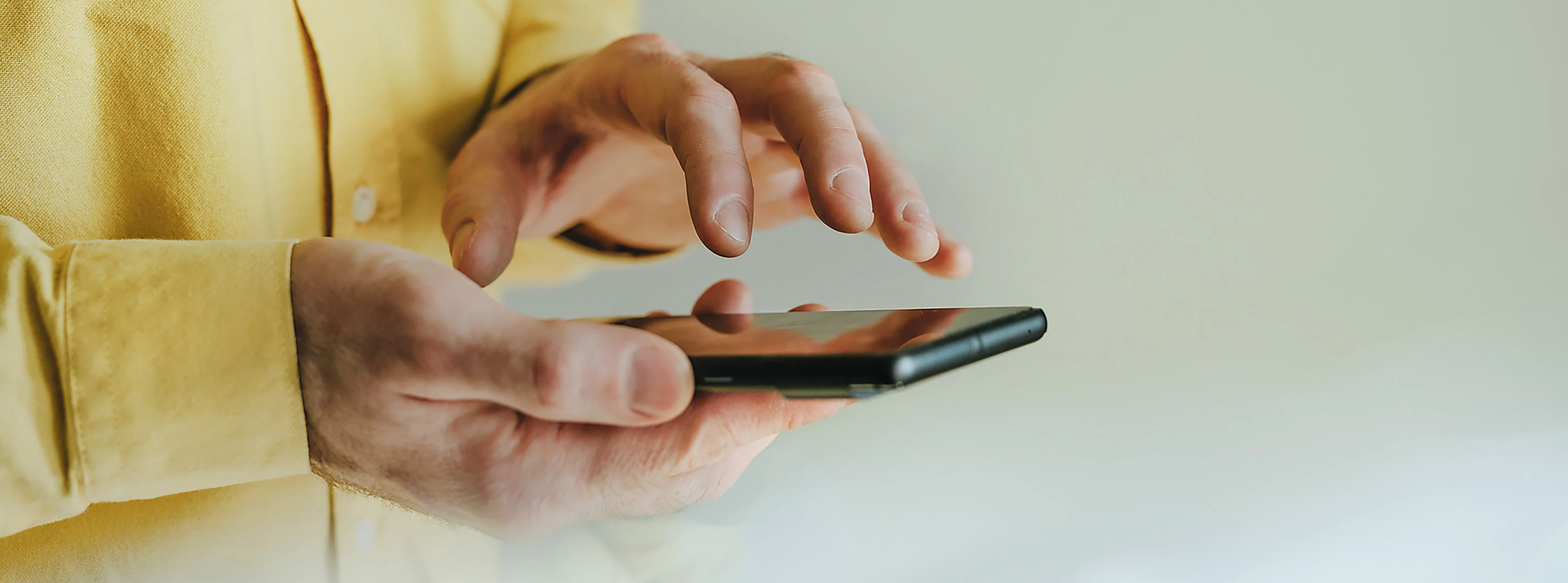 Eine Person hält ein Smartphone in der Hand und tippt darauf.