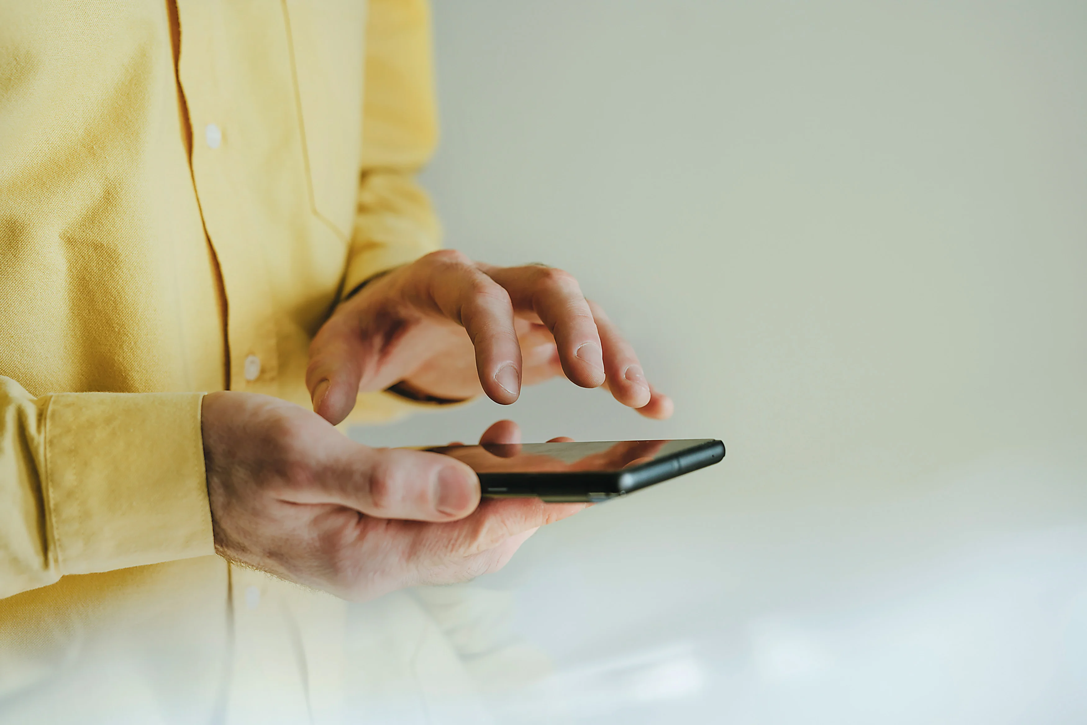 Eine Person hält ein Smartphone in der Hand und tippt darauf.